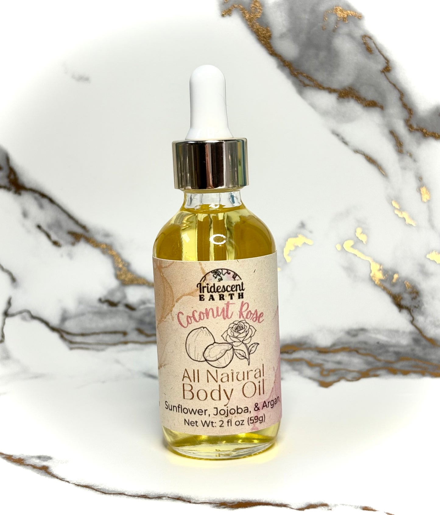 Bottle of all natural coconut rose scented body oil with a dropper on a marble surface