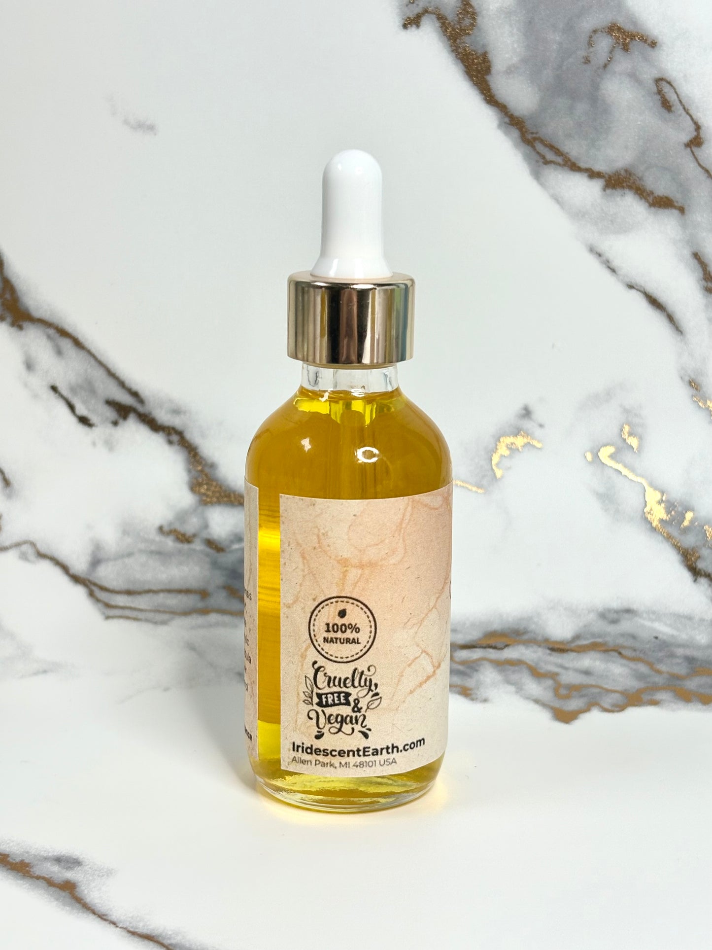 Bottle of oil with a dropper on a marble surface. Label has 100% natural logo, and cruelty free & vegan logo