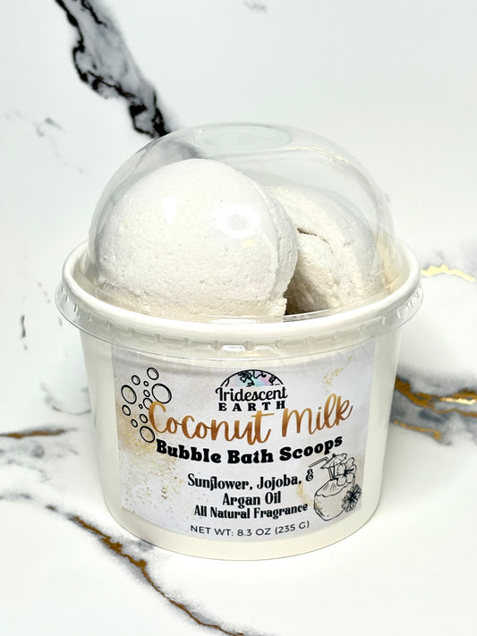 Container of coconut milk bubble bath scoops on a marble surface