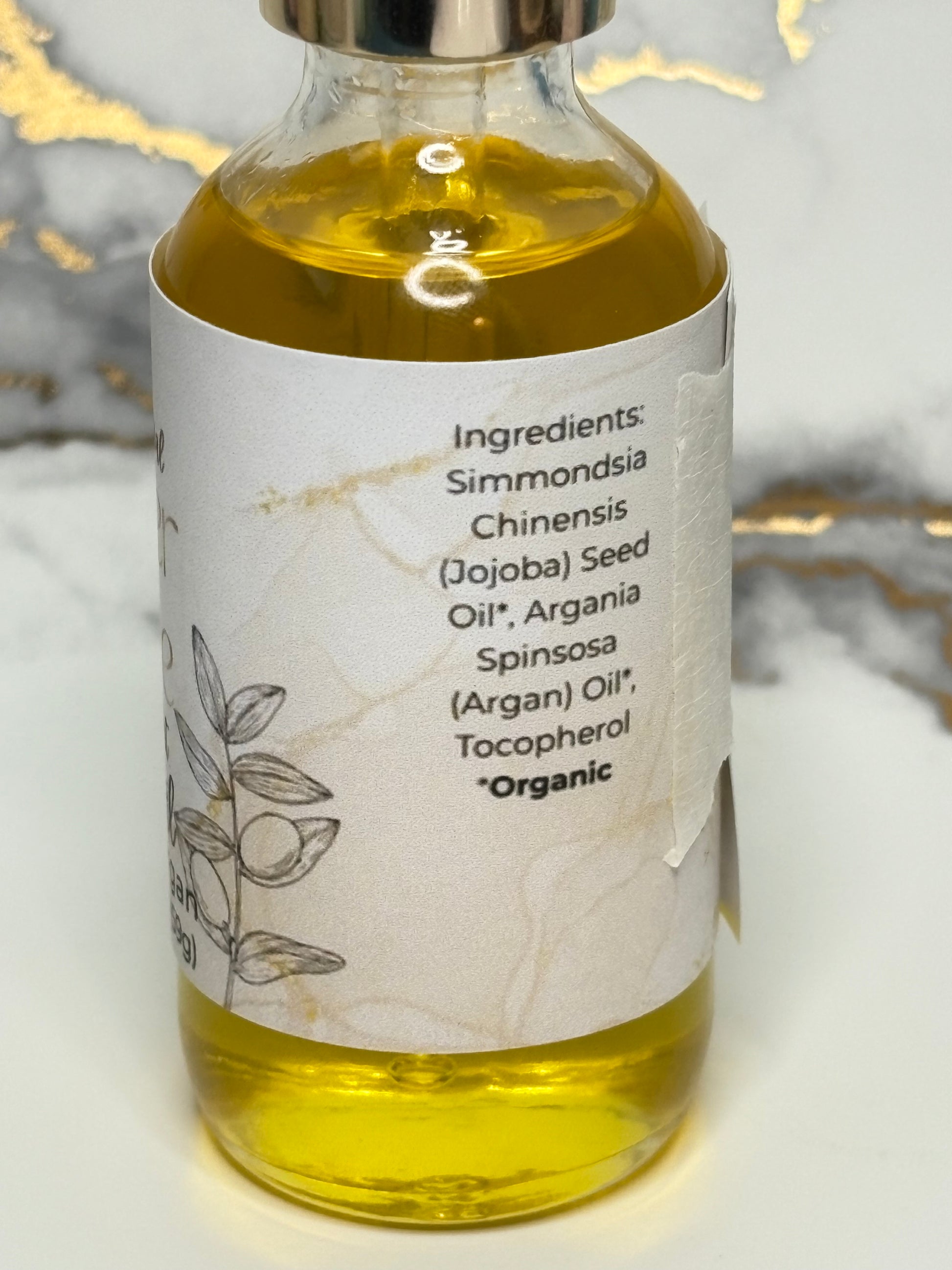 Bottle of oil for hair with a label on a marble surface