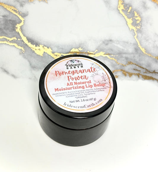 Black container of 'Pomegranate Power' lip balm on a marble background