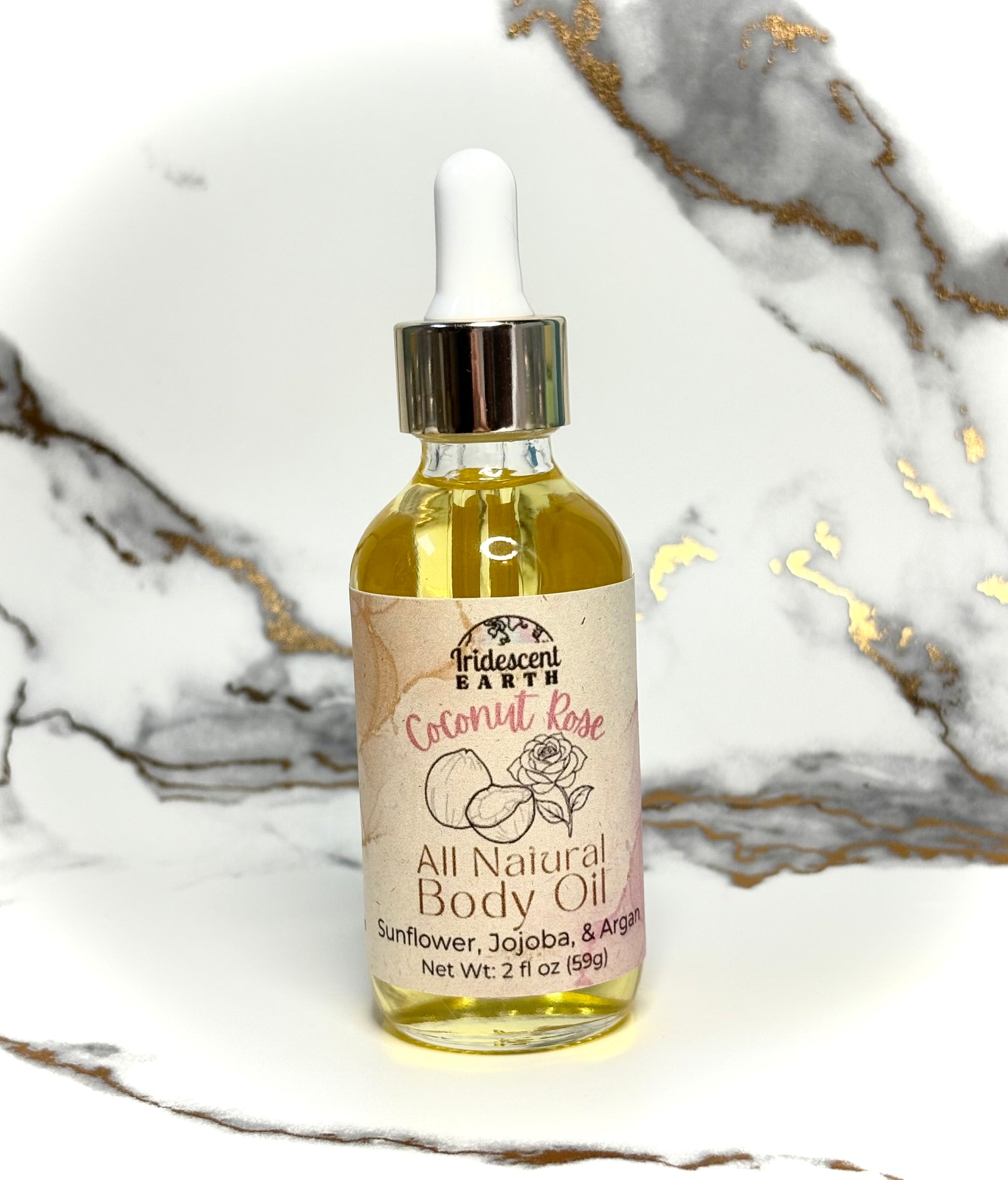 Bottle of all natural coconut rose scented body oil with a dropper on a marble surface