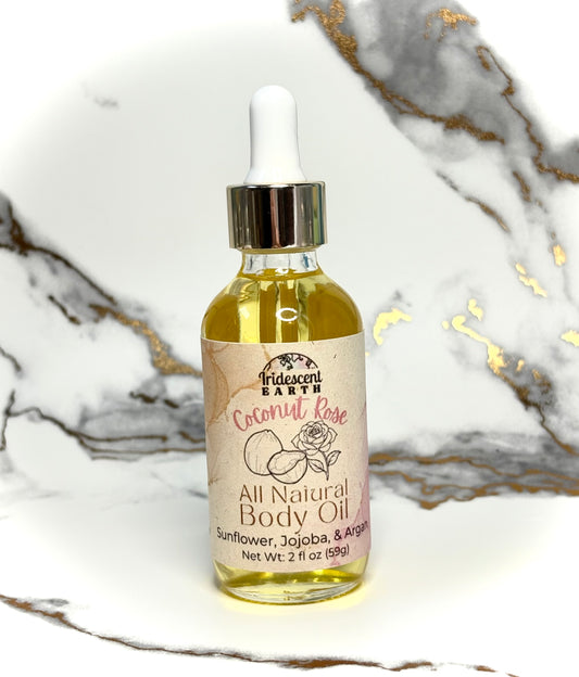 Bottle of all natural coconut rose scented body oil with a dropper on a marble surface